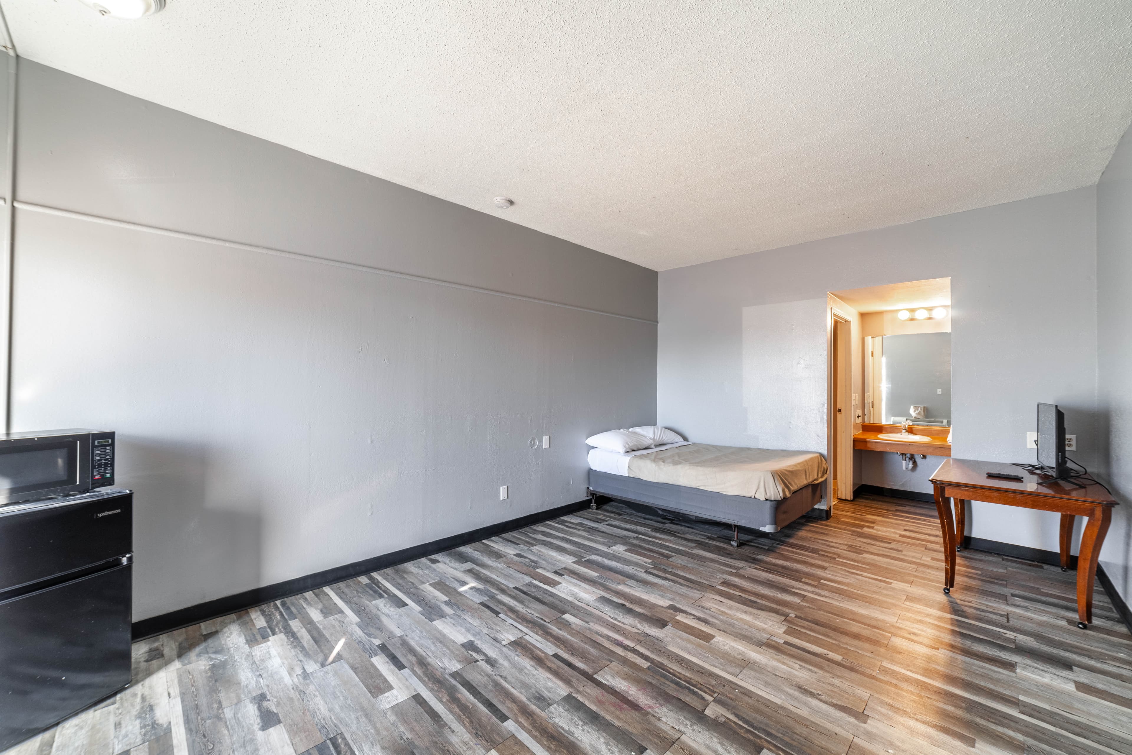 Guest room with a bed, mini fridge, microwave, and desk